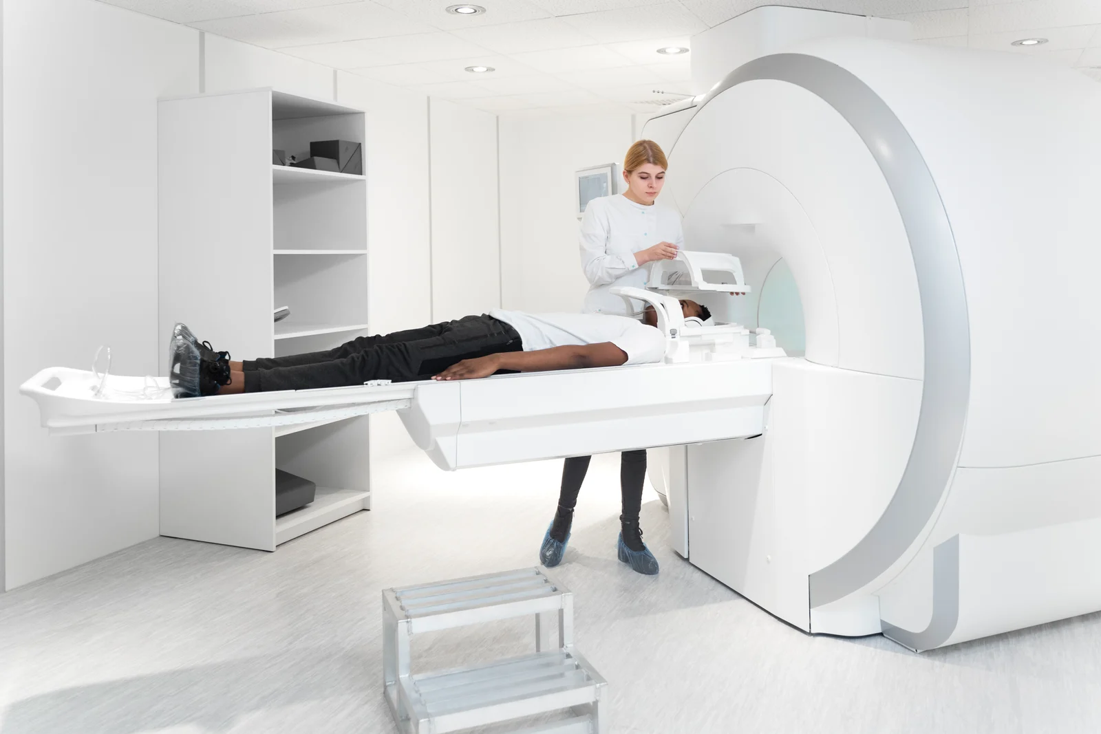 A clinician preparing a patient for an MRI scan in a bright, white imaging room